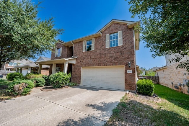 traditional-style house featuring brick siding, concrete driveway, an attached garage, fence, and a front yard