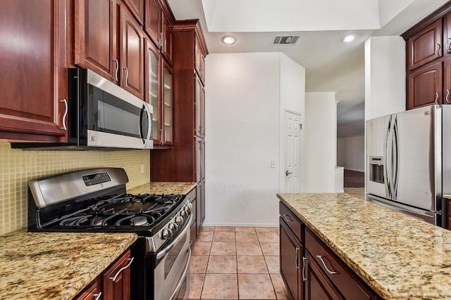 6303 Needham Ln, Austin, TX 78739 - kitchen with stainless steel appliances, tasteful backsplash, light stone countertops, and reddish brown cabinets