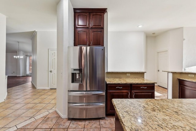 6303 Needham Ln, Austin, TX 78739 - kitchen featuring stainless steel refrigerator with ice dispenser, light tile patterned floors, a chandelier, light stone countertops, and baseboards