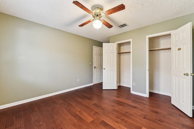 6303 Needham Ln, Austin, TX 78739 - unfurnished bedroom featuring two closets, a textured ceiling, dark wood finished floors, baseboards, and ceiling fan
