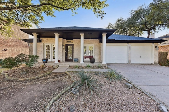 6303 Needham Ln, Austin, TX 78739 - view of front of home with french doors, concrete driveway, a garage, a porch, and stone siding