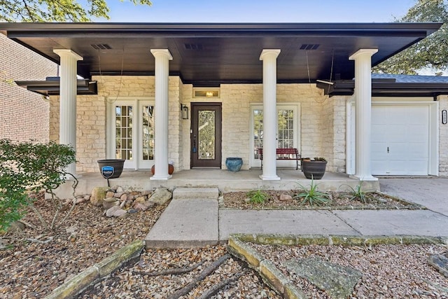 6303 Needham Ln, Austin, TX 78739 - view of exterior entry featuring a porch, stone siding, an attached garage, and driveway