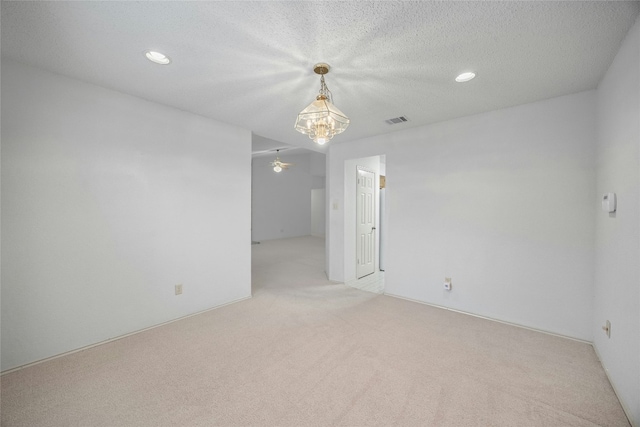 spare room with light colored carpet, visible vents, a textured ceiling, and recessed lighting