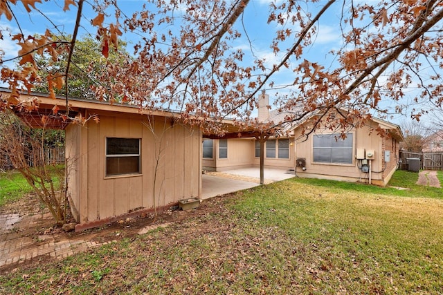 rear view of property with a patio area, a chimney, fence, and a yard