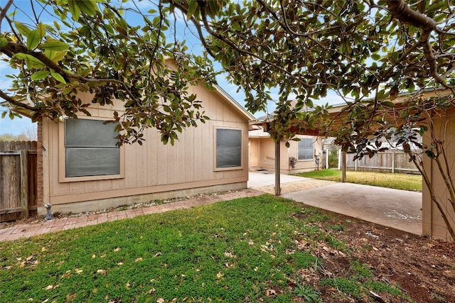 view of side of home featuring a patio, a lawn, and fence