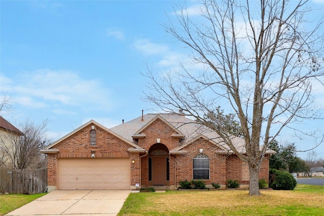 traditional-style home with brick siding, an attached garage, a front yard, fence, and driveway