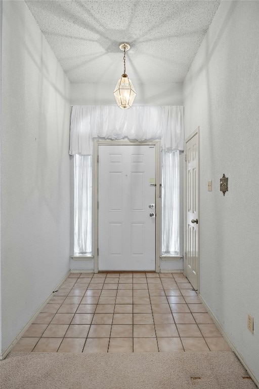 entrance foyer with light carpet, light tile patterned floors, and a textured ceiling