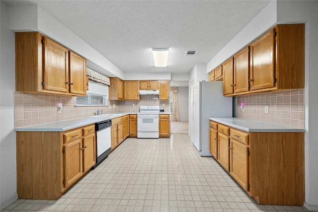 kitchen with white appliances, under cabinet range hood, visible vents, and light countertops