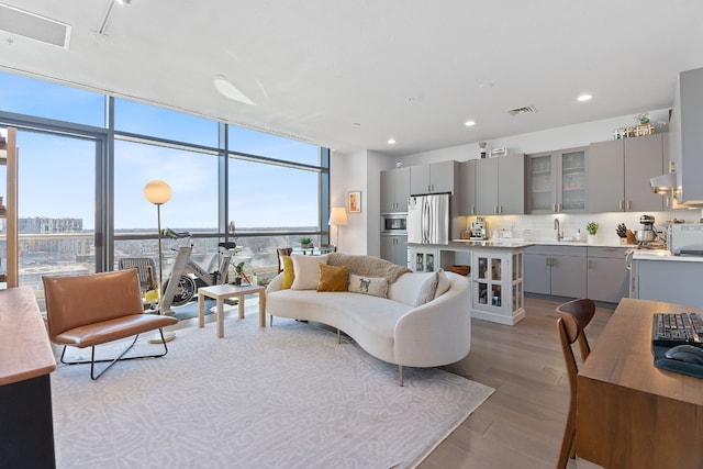 living room featuring light wood-style floors, visible vents, floor to ceiling windows, and recessed lighting