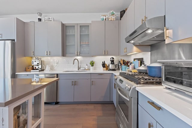 kitchen featuring gray cabinets, appliances with stainless steel finishes, a sink, extractor fan, and backsplash