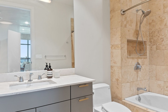 bathroom with tiled shower / bath, vanity, and toilet
