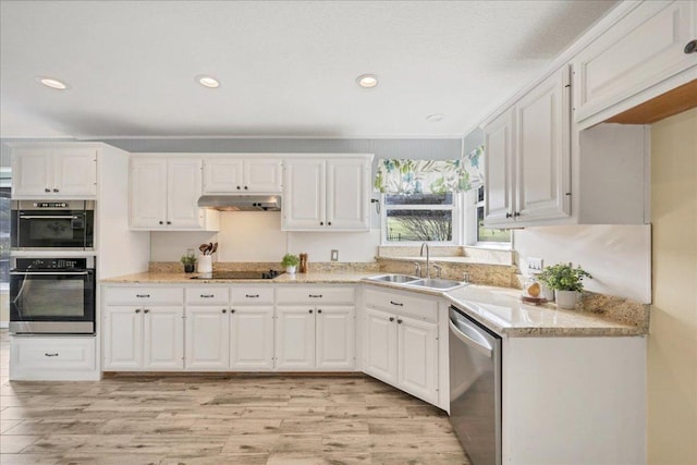 kitchen with stainless steel appliances, light wood-type flooring, under cabinet range hood, white cabinetry, and a sink