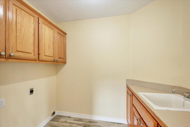 laundry room featuring cabinet space, baseboards, a sink, light wood-type flooring, and electric dryer hookup