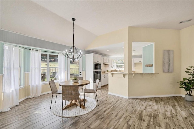 dining space with visible vents, light wood-style flooring, vaulted ceiling, a chandelier, and baseboards