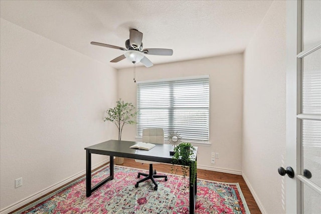 home office with a ceiling fan, a textured ceiling, baseboards, and wood finished floors