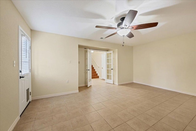 empty room with ceiling fan, light tile patterned flooring, and baseboards