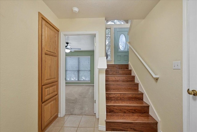 staircase with carpet floors, a wealth of natural light, a textured ceiling, and tile patterned floors