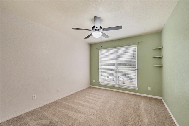 carpeted spare room featuring ceiling fan and baseboards