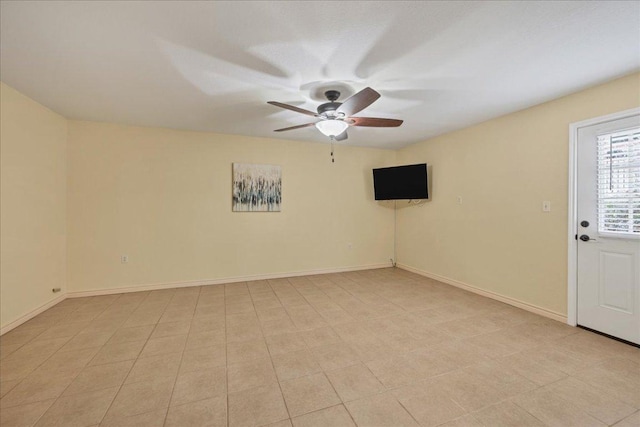 spare room featuring a ceiling fan and baseboards