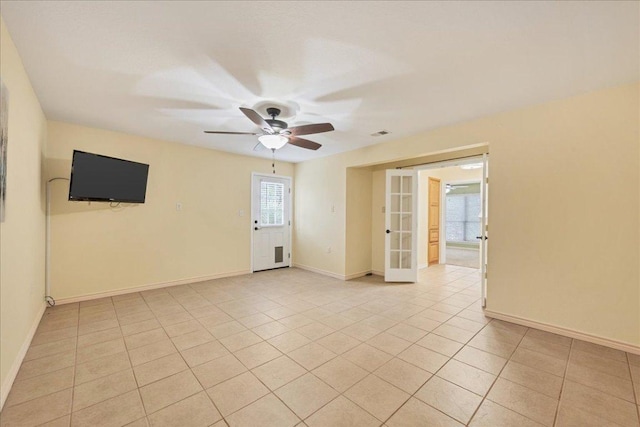 empty room featuring a healthy amount of sunlight, light tile patterned floors, baseboards, and french doors