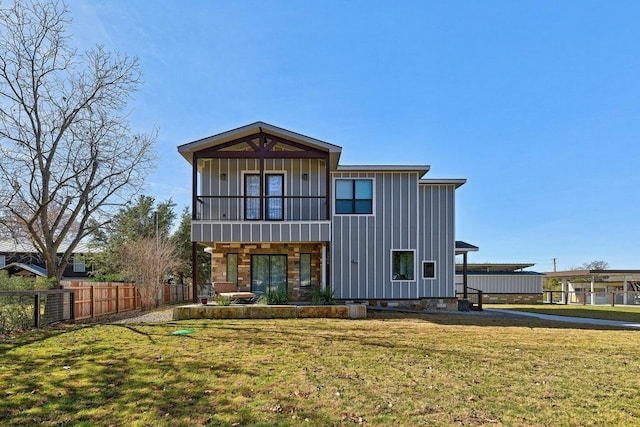 rear view of property with board and batten siding, fence, and a lawn