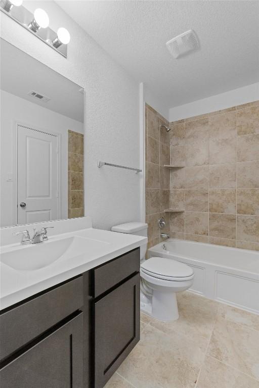 full bath with washtub / shower combination, a textured ceiling, vanity, and visible vents