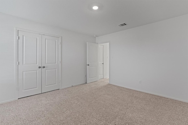 unfurnished bedroom featuring a closet, visible vents, light carpet, and baseboards