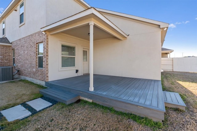 back of property with a deck, central AC, brick siding, fence, and stucco siding