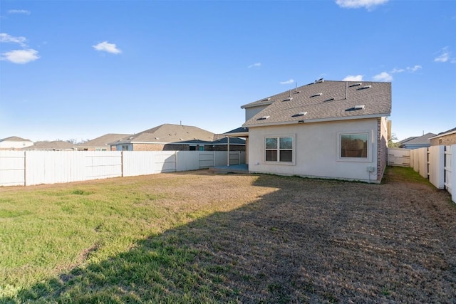 rear view of house with a yard, a fenced backyard, and stucco siding