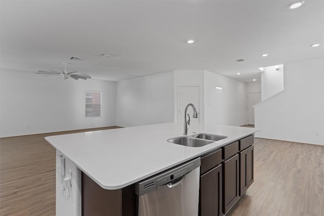 kitchen featuring dishwasher, an island with sink, open floor plan, light countertops, and a sink