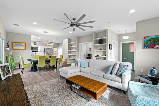 living area featuring baseboards, wood finished floors, visible vents, and recessed lighting