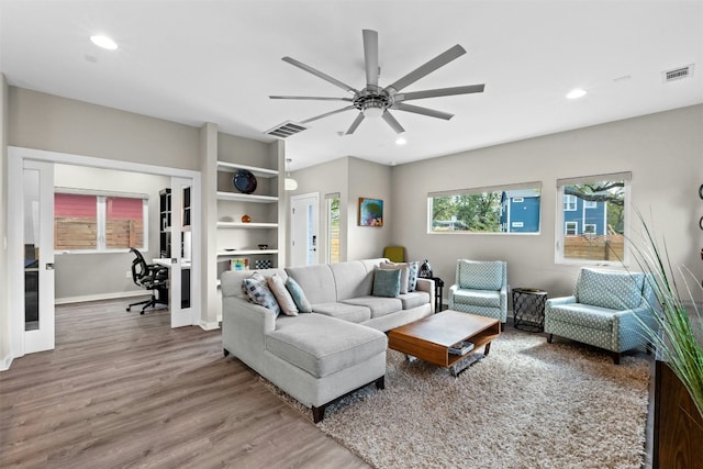 living area featuring baseboards, wood finished floors, visible vents, and recessed lighting