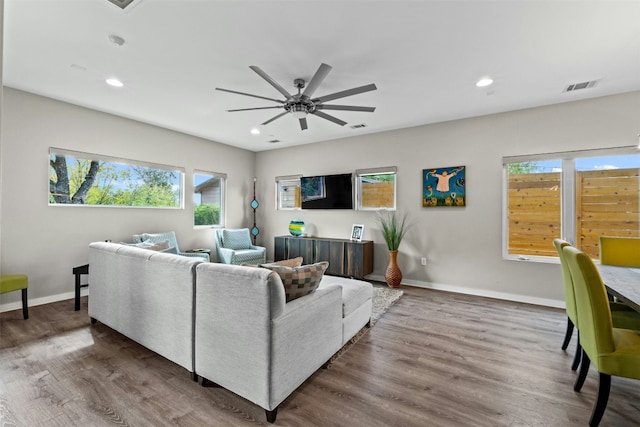 living room with recessed lighting, visible vents, baseboards, and wood finished floors