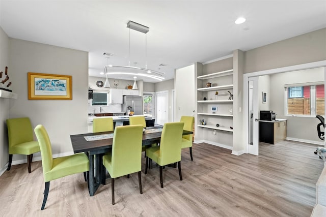 dining space with light wood-type flooring, plenty of natural light, visible vents, and baseboards