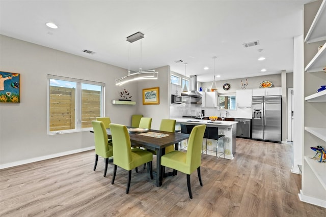 dining space featuring baseboards, visible vents, and light wood-style floors