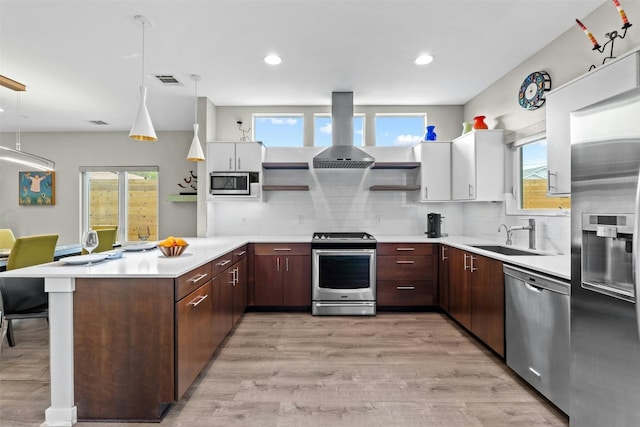 kitchen with island range hood, appliances with stainless steel finishes, a peninsula, open shelves, and a sink