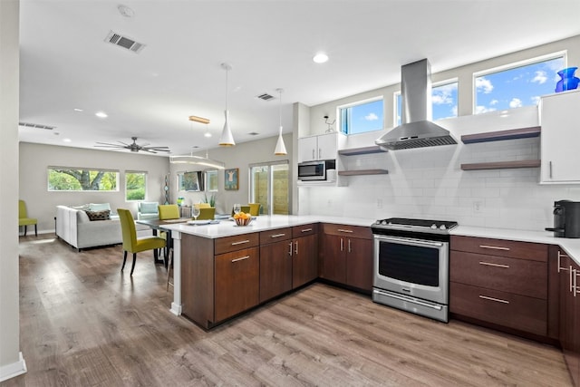 kitchen featuring visible vents, island range hood, a peninsula, stainless steel appliances, and open shelves