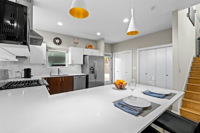 kitchen with decorative backsplash, appliances with stainless steel finishes, a breakfast bar, light countertops, and a sink