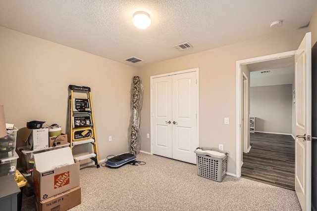 misc room with carpet floors, visible vents, and a textured ceiling