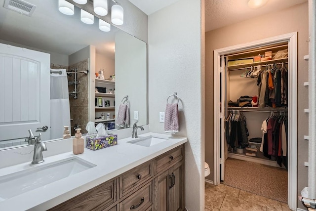 bathroom featuring double vanity, a spacious closet, visible vents, and a sink