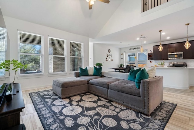 living area featuring light wood-style floors, ceiling fan, high vaulted ceiling, and a wealth of natural light