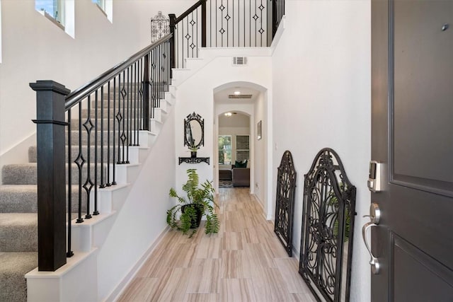 entrance foyer featuring a towering ceiling, wood finished floors, visible vents, and baseboards