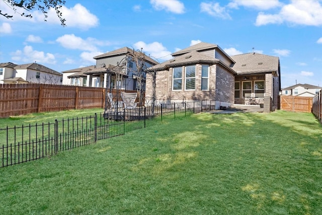 rear view of property featuring a patio area, a fenced backyard, brick siding, and a yard