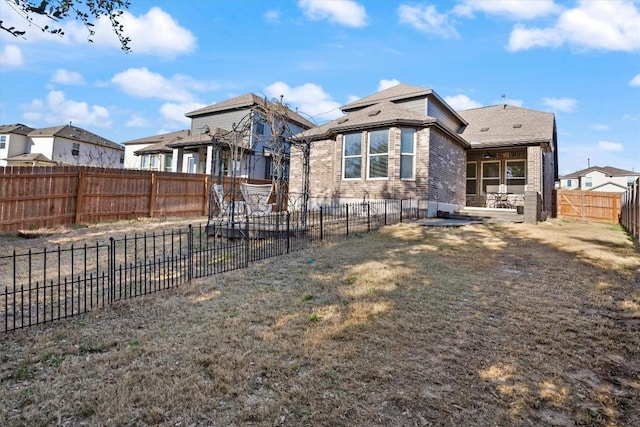 back of property featuring brick siding, a fenced backyard, a lawn, and a patio