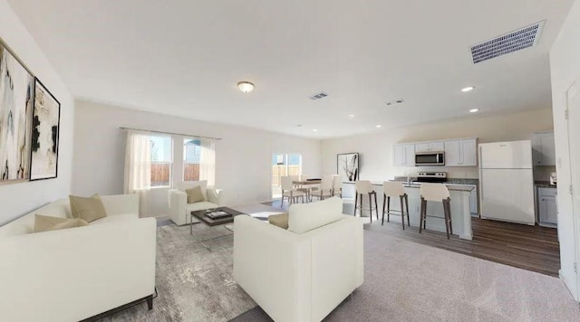 living room featuring light wood-style flooring, visible vents, and recessed lighting