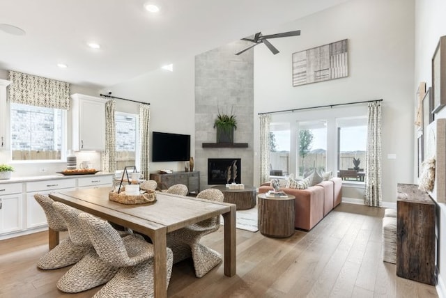 living area featuring light wood-style floors, plenty of natural light, a fireplace, and high vaulted ceiling