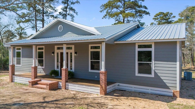 view of front of home with covered porch, metal roof, and central air condition unit