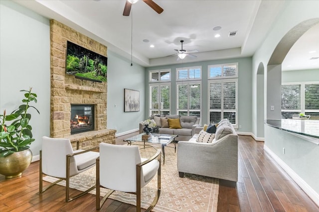 living room with a stone fireplace, baseboards, and wood finished floors