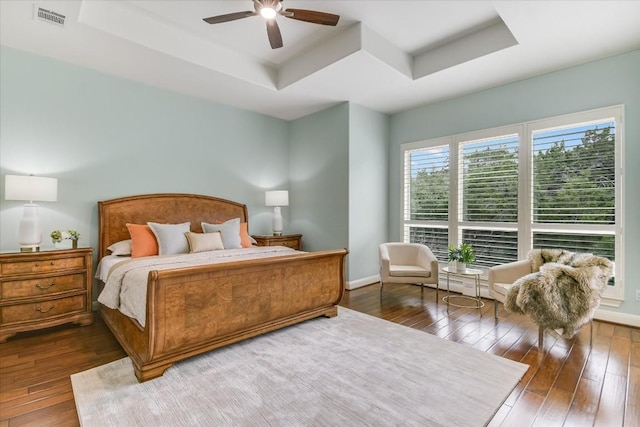 bedroom featuring dark wood-type flooring, a raised ceiling, and baseboards