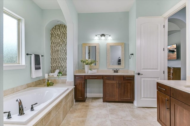 bathroom with a garden tub, vanity, and tile patterned floors